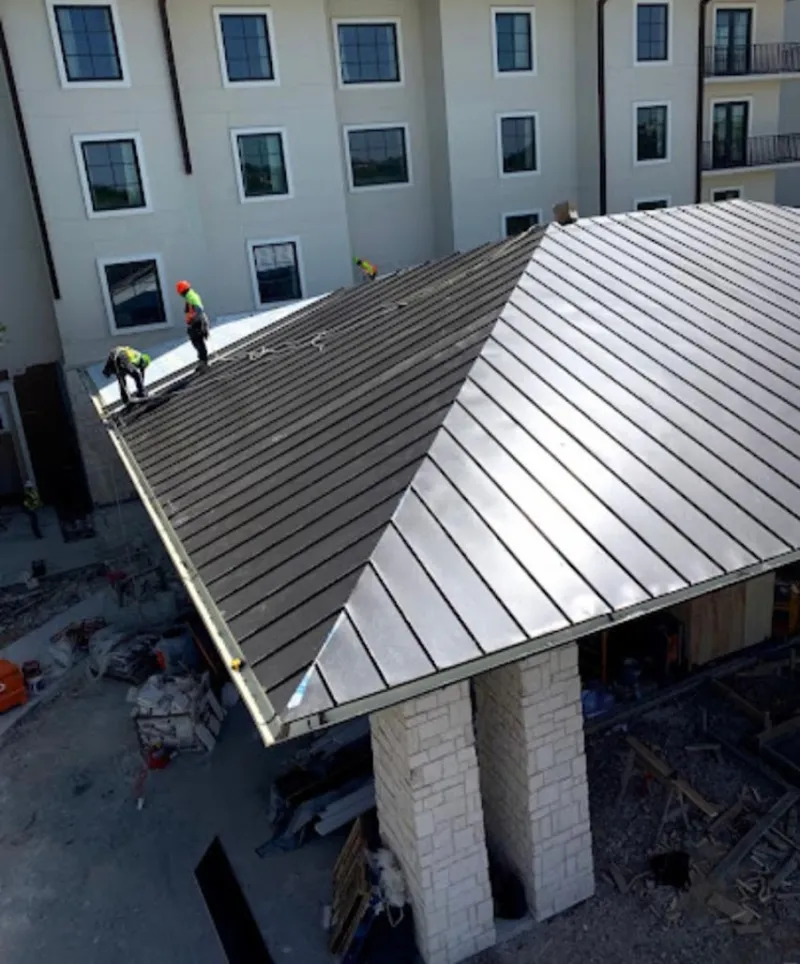 Crew installing standing seam metal roof panels on a commercial project in Clarkston